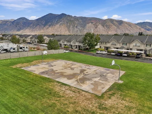 Outdoor basketball court with two hoops, surrounded by a grassy area and framed by distant mountains