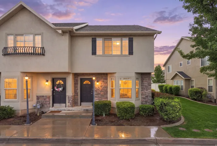 Stucco exterior featuring stone accents, a decorative Juliet balcony, and prominent bay windows