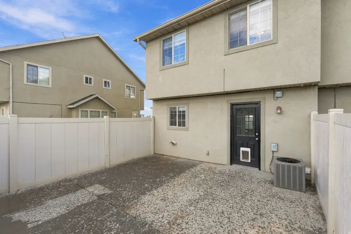 Enclosed patio area with a privacy fence, concrete surface, and stucco exterior