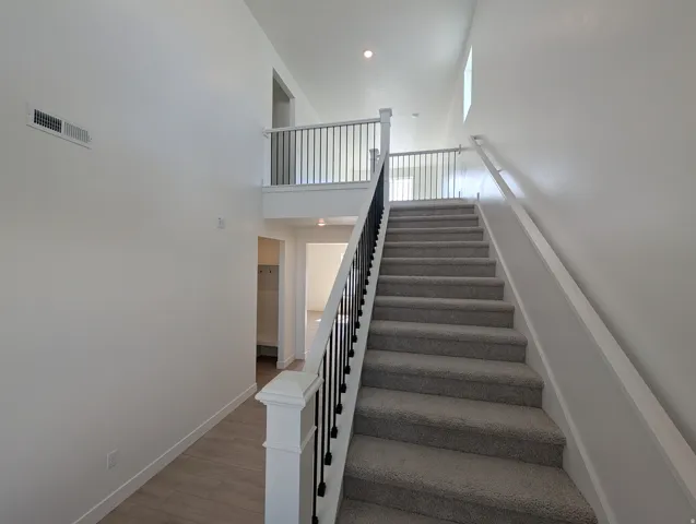Two-story entry with carpeted staircase, a white baluster railing, and a second-story landing