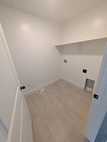 Built-in shelving, tile flooring, white walls, black door hardware, and essential utility connections