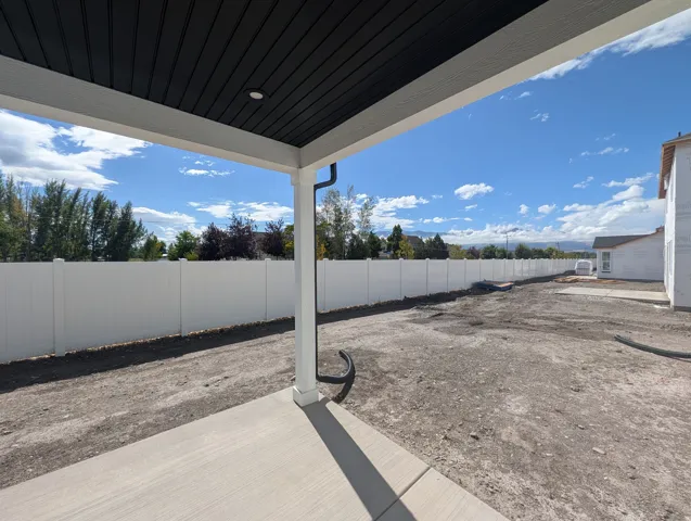 Covered patio with a concrete surface, featuring a recessed light and dark soffit