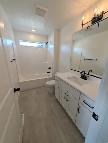 White vanity with black hardware, rectangular undermount sink, and light-toned countertop