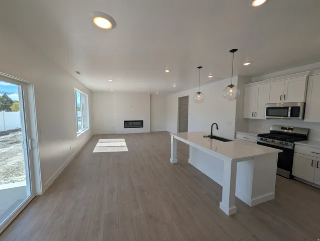 Open concept living space featuring wood-finish flooring, recessed lighting, and a linear fireplace