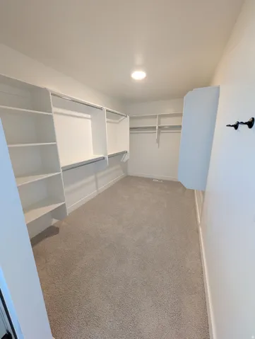 Recessed lighting, light gray carpeting, and white built-in shelving with hanging rods