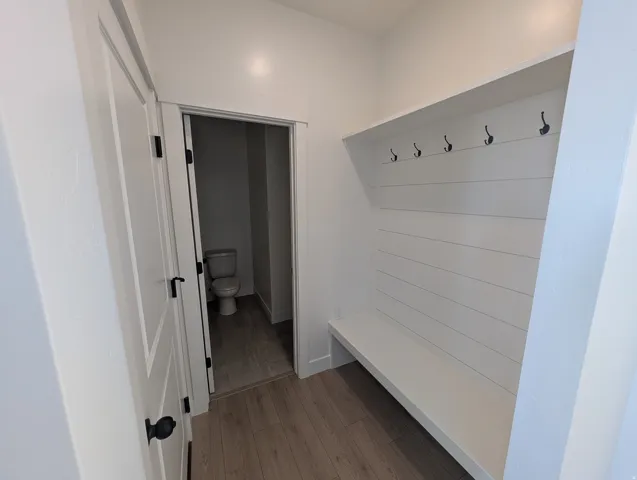 Built-in bench with shiplap backing, five coat hooks, and wood-finish flooring