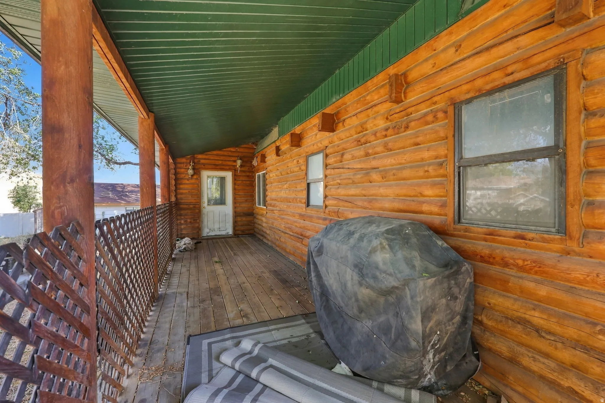 Expansive covered porch featuring wood-finish siding, durable wood-finish decking, and a green corrugated metal ceiling