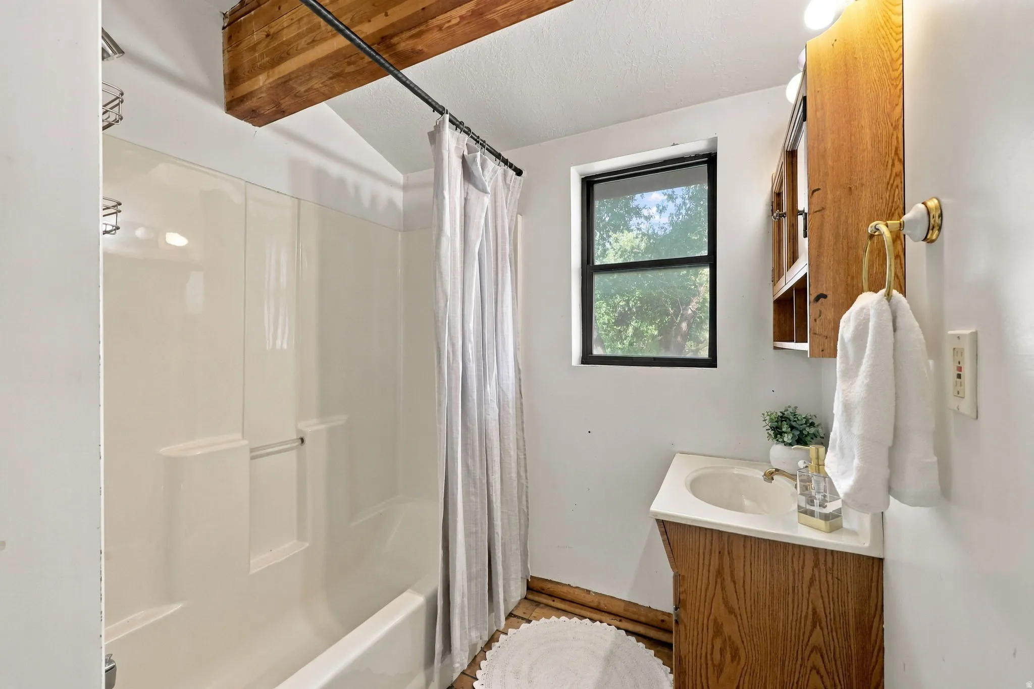 Wood-finish vanity with an integrated sink, built-in medicine cabinet, and a window with a dark frame