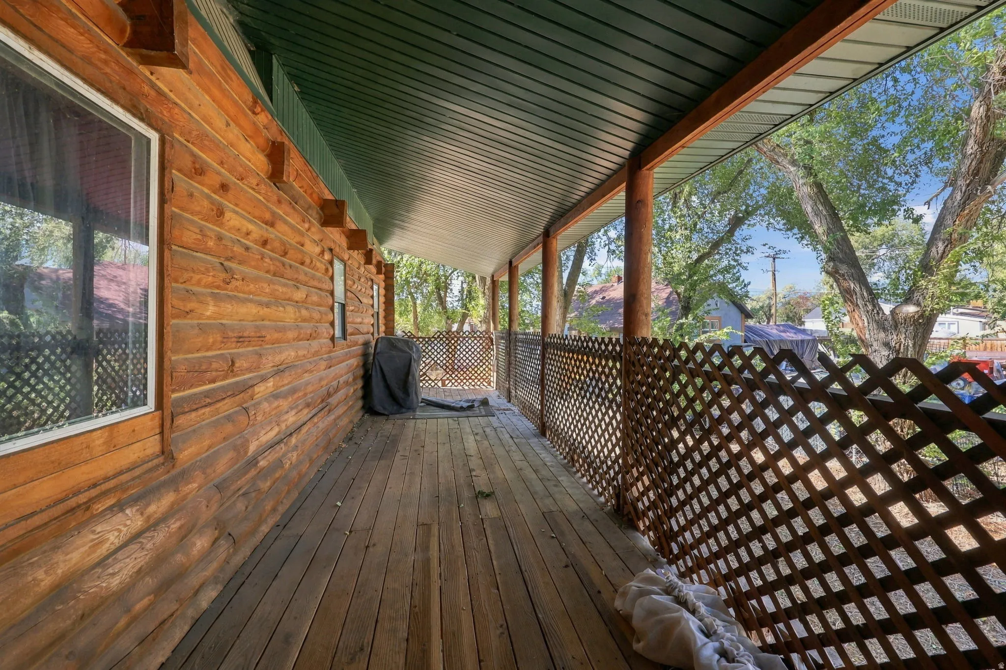 Wood-sided exterior featuring a covered porch with wood flooring, lattice railing, and wood support beams
