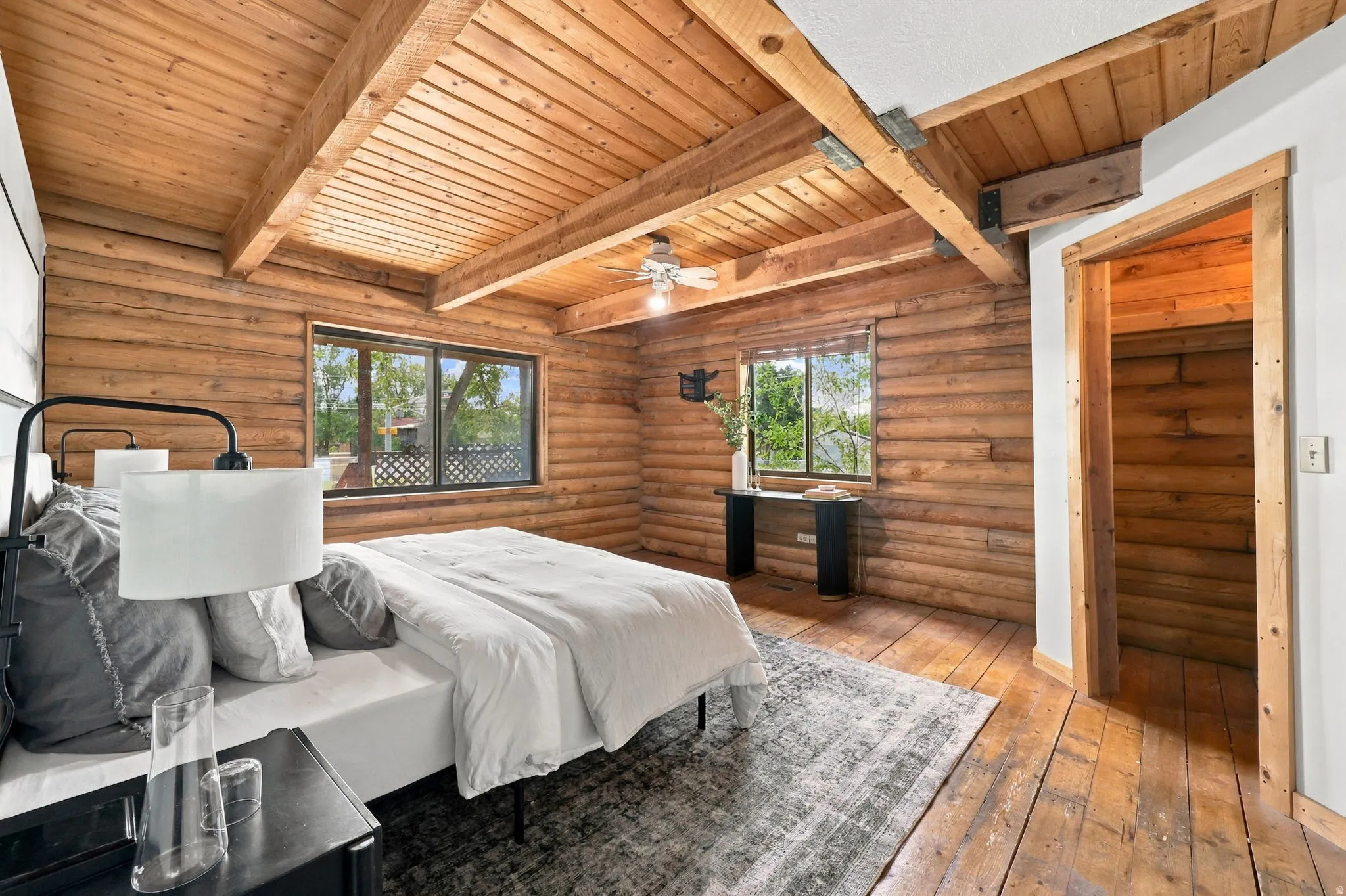 Exposed wood log walls, rustic wood-plank flooring, and wood-paneled vaulted ceilings with exposed beams