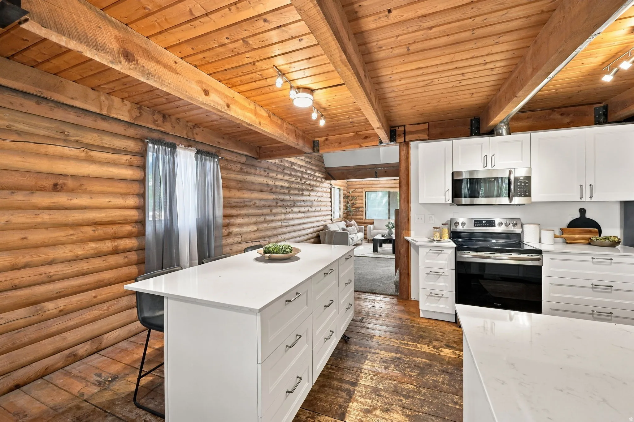 Kitchen featuring white cabinetry, stainless steel appliances, and a central island with a white countertop