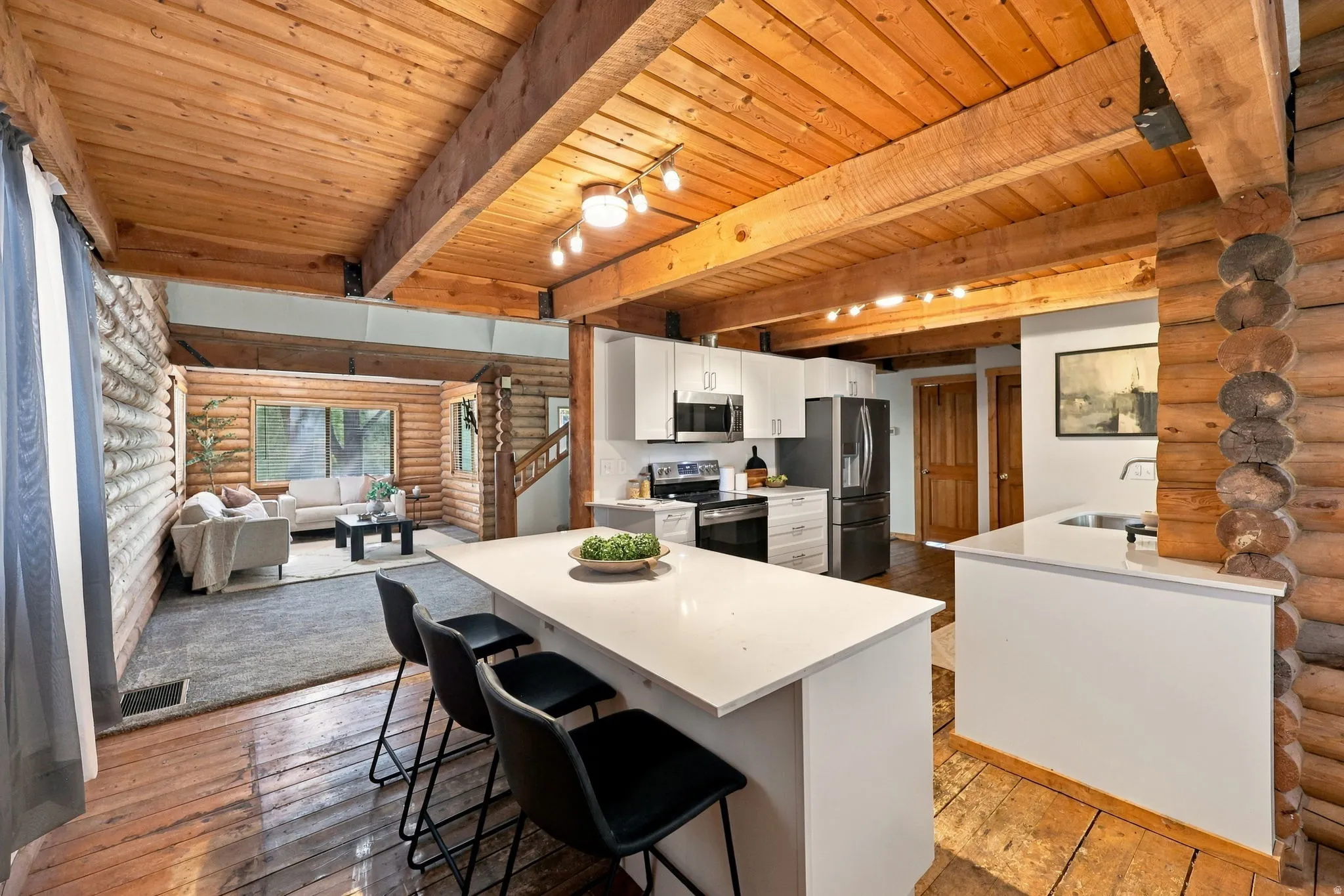 Open-concept kitchen featuring an island with seating, white cabinetry, and stainless steel appliances