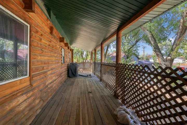 Wood-sided exterior featuring a covered porch with wood flooring, lattice railing, and wood support beams