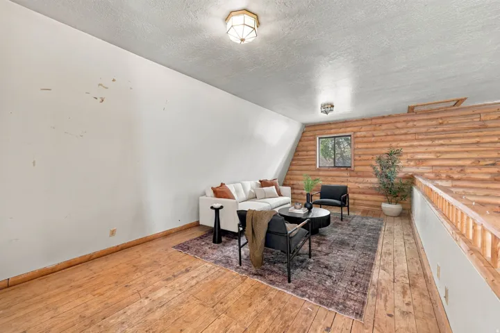 Wood-finish flooring, wood plank accent wall, sloped ceiling, and overhead lighting