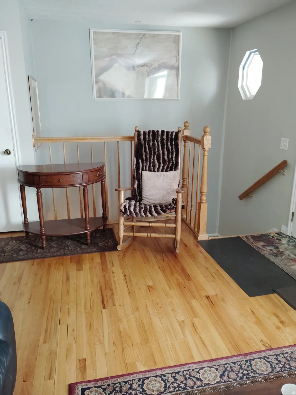 Hardwood flooring, light wood banister, and an octagonal window