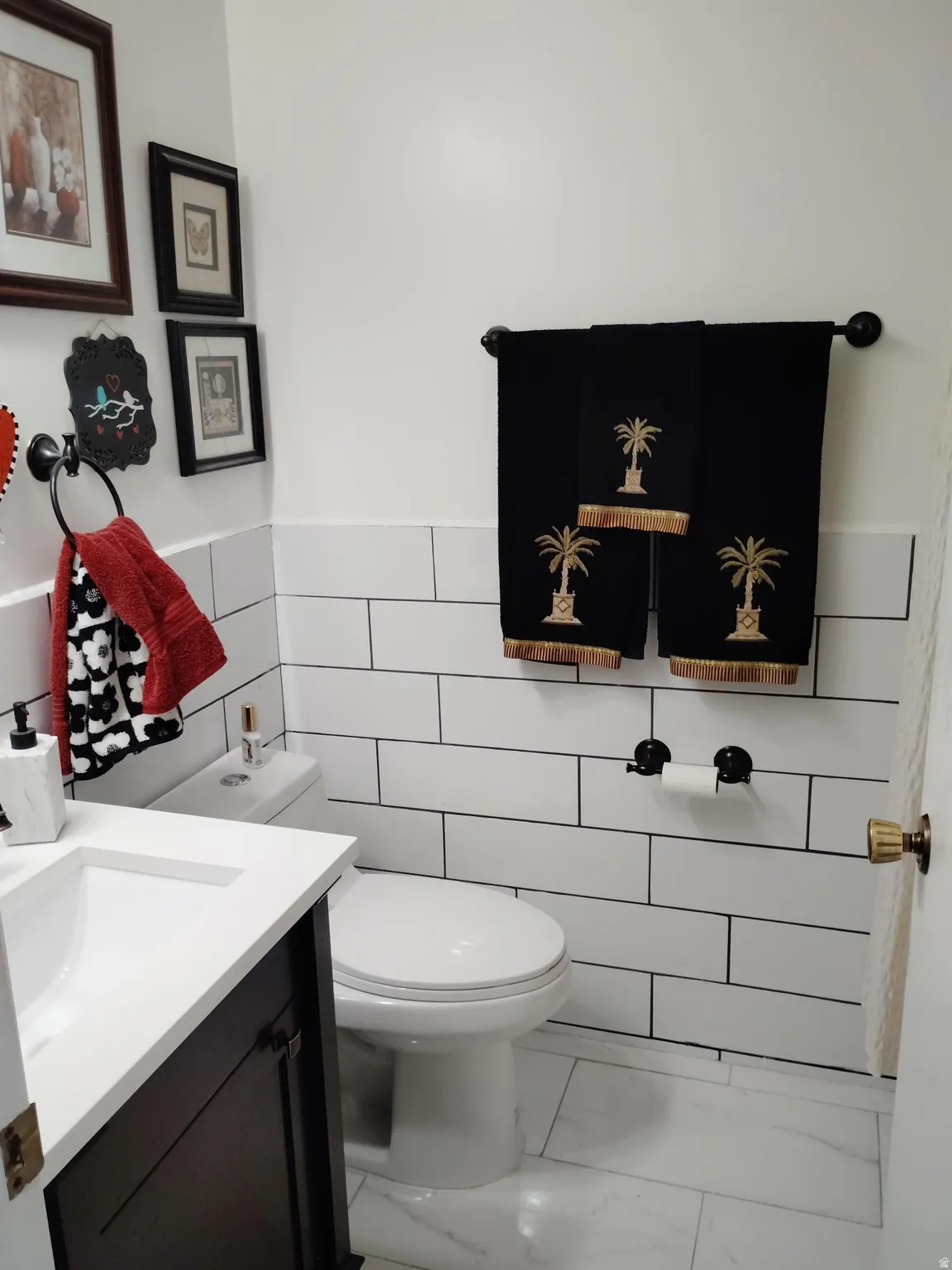 Bathroom featuring subway tile wainscoting, white walls, and a dark wood-finish vanity with a white countertop