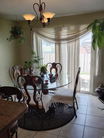 Sliding glass door, tiled flooring, built-in overhead lighting fixture, window with sheer drapery, and a granite-finish countertop