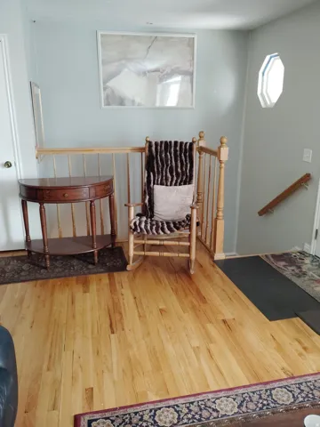 Hardwood flooring, light wood banister, and an octagonal window