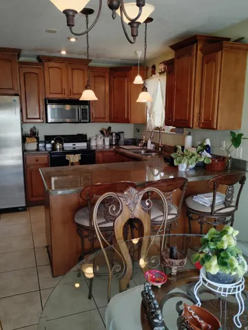 Kitchen featuring wood cabinetry, stainless steel appliances, a multi-level breakfast bar, and tile flooring