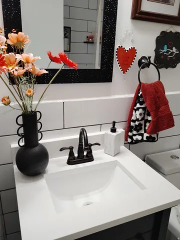 White countertop with an integrated sink, bronze-finish faucet, and subway tile backsplash
