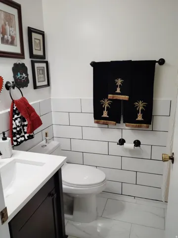 Bathroom featuring subway tile wainscoting, white walls, and a dark wood-finish vanity with a white countertop