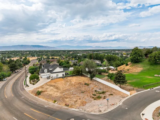 Expansive lot with a gradual slope, bordered by a white privacy fence