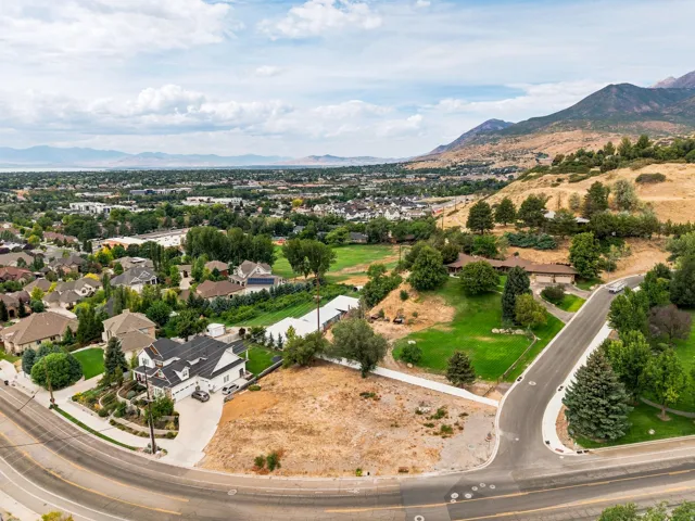 Expansive lot with mountain backdrop, residential surroundings, and paved road access
