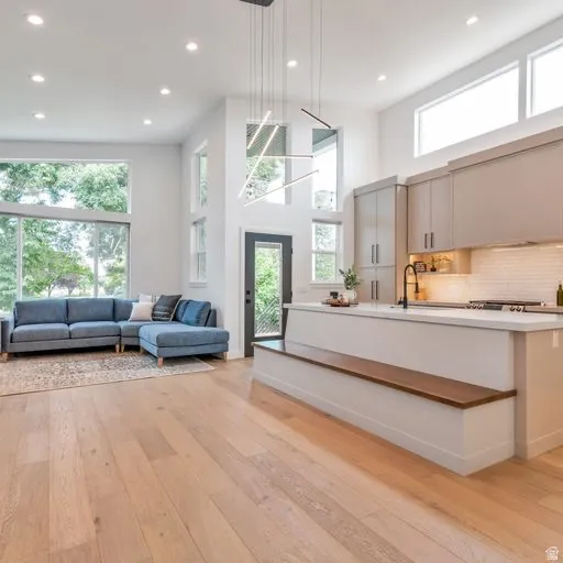 High ceilings with recessed lighting, large windows, wood-finish flooring, a kitchen island with built-in seating, and a modern linear chandelier