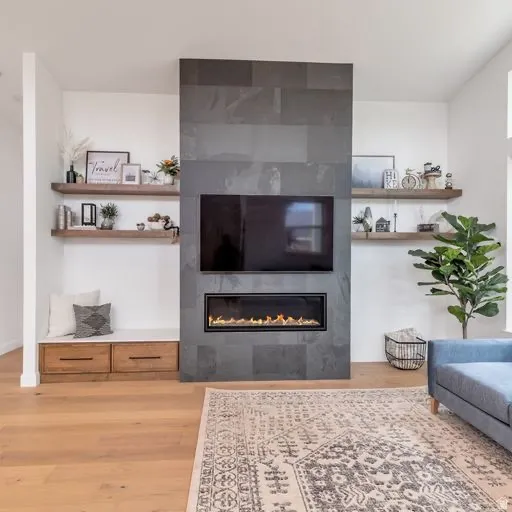 Stacked stone fireplace with an integrated linear firebox, wood-finish flooring, and built-in shelving with integrated bench seating