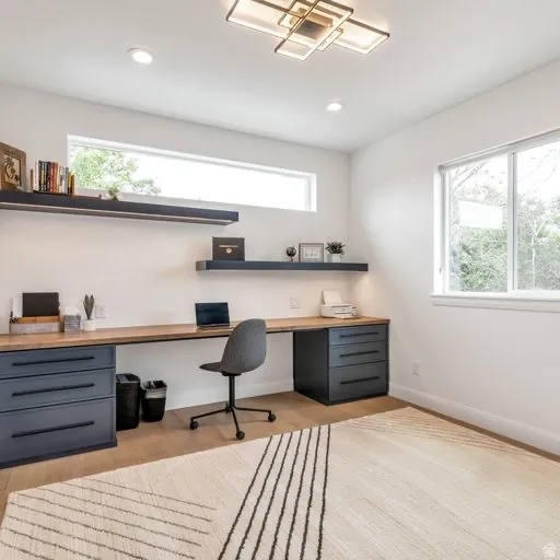 Built-in wood-finish desktop with integrated storage drawers, recessed lighting, and a contemporary ceiling fixture