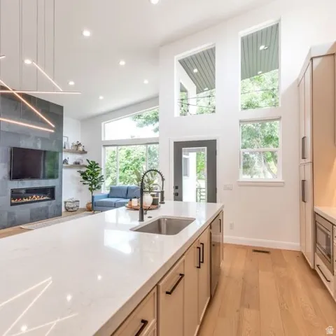 Open-concept living area with high ceilings, featuring a large kitchen island with a built-in sink and a sleek fireplace with a stone surround