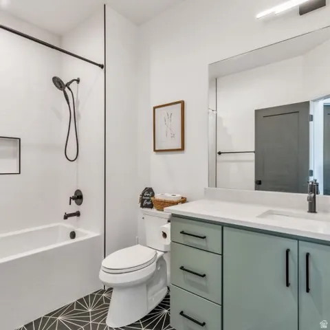 Modern bathroom featuring a white bathtub/shower combination with black fixtures, a patterned floor, and a vanity with a white countertop