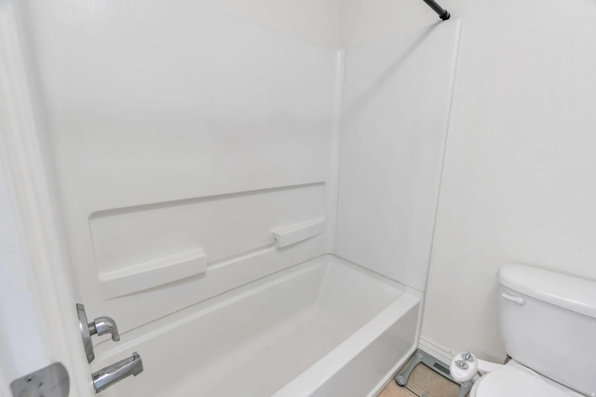Bathtub with integrated shelving, chrome fixtures, and a white surround