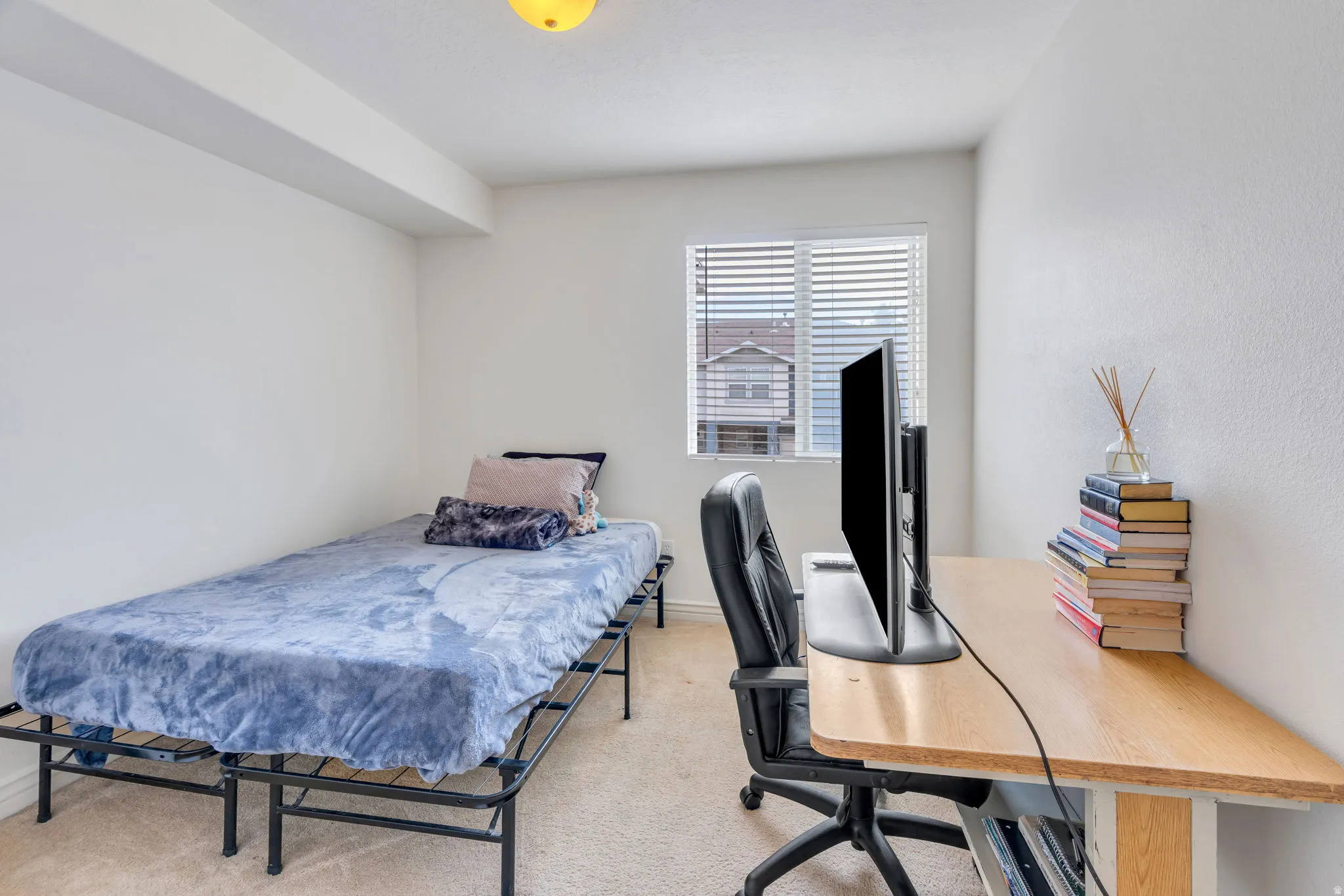 Neutral wall finishes, light carpeting, window with horizontal blinds, and overhead lighting
