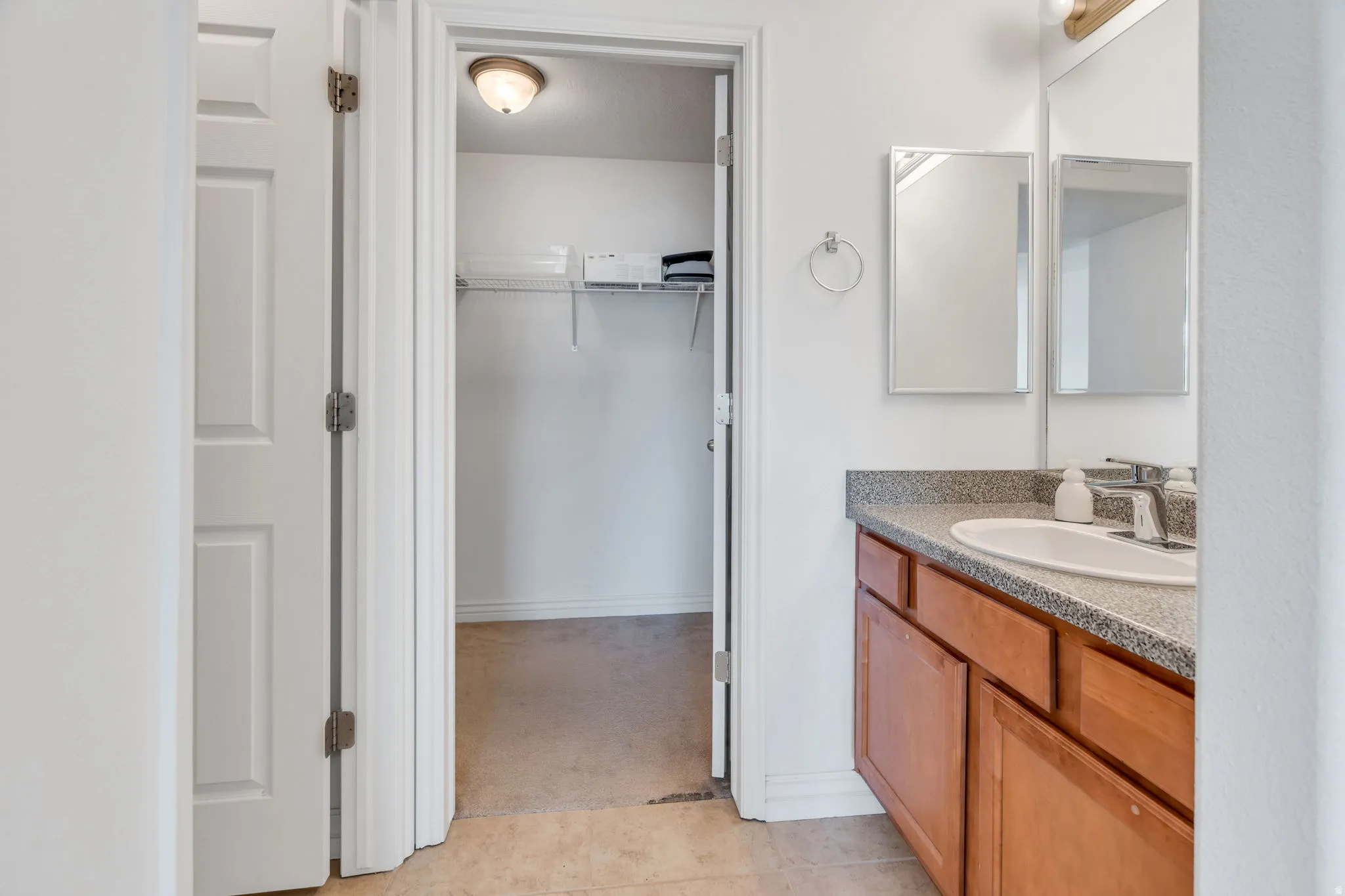 Bathroom vanity with a single basin sink, a speckled countertop, and warm-toned wood cabinetry