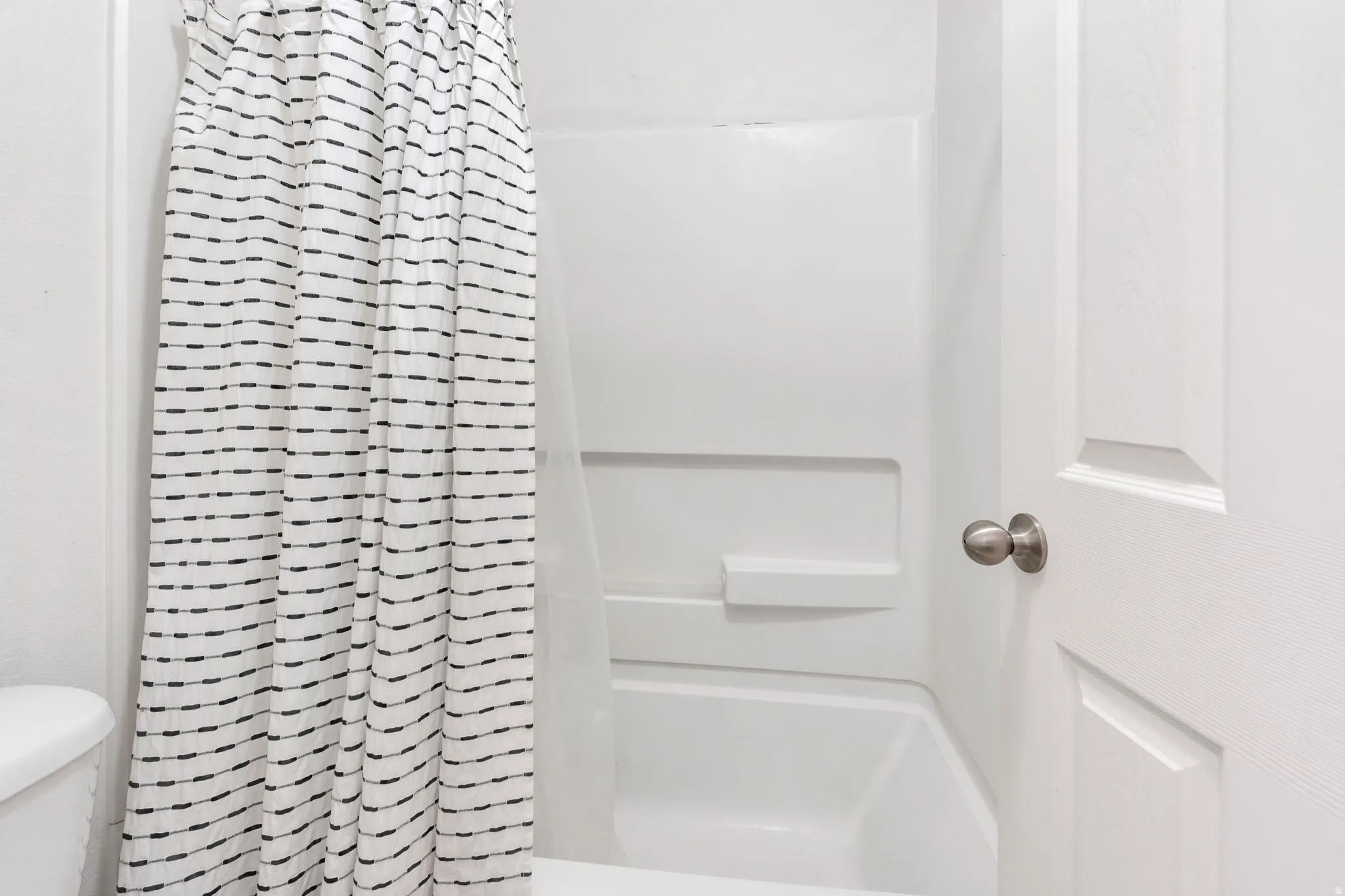 White tub and shower combination with integrated shelving