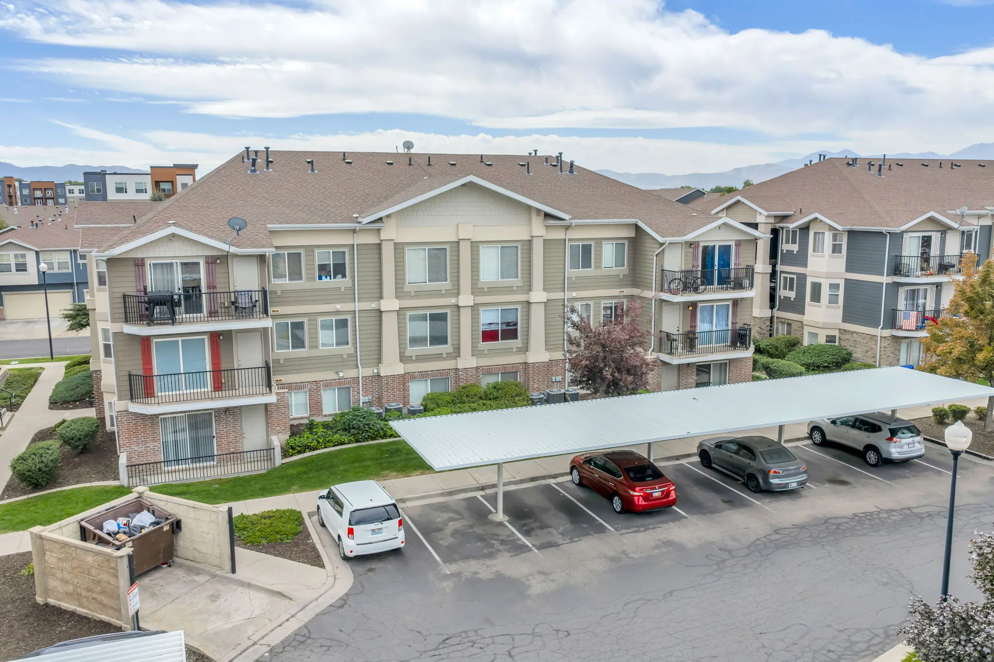 Multi-story building featuring balconies, brick detailing, and a neutral color palette