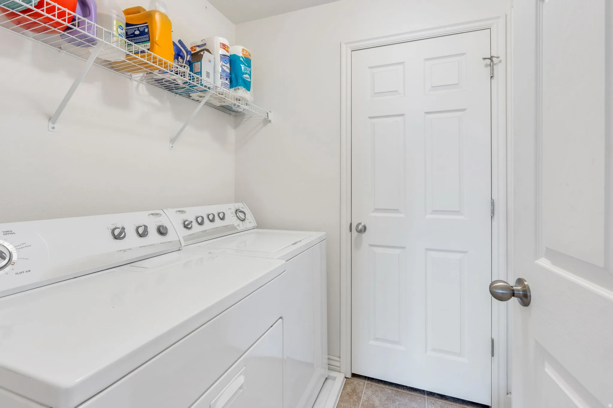 Utility area featuring white walls, wire shelving, and tiled flooring