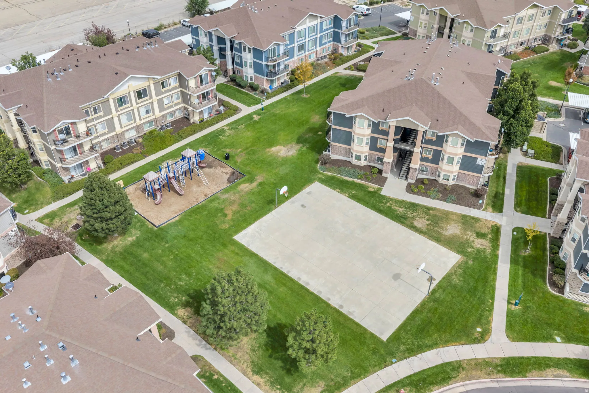 Manicured grounds featuring a playground, basketball court, and pedestrian pathways