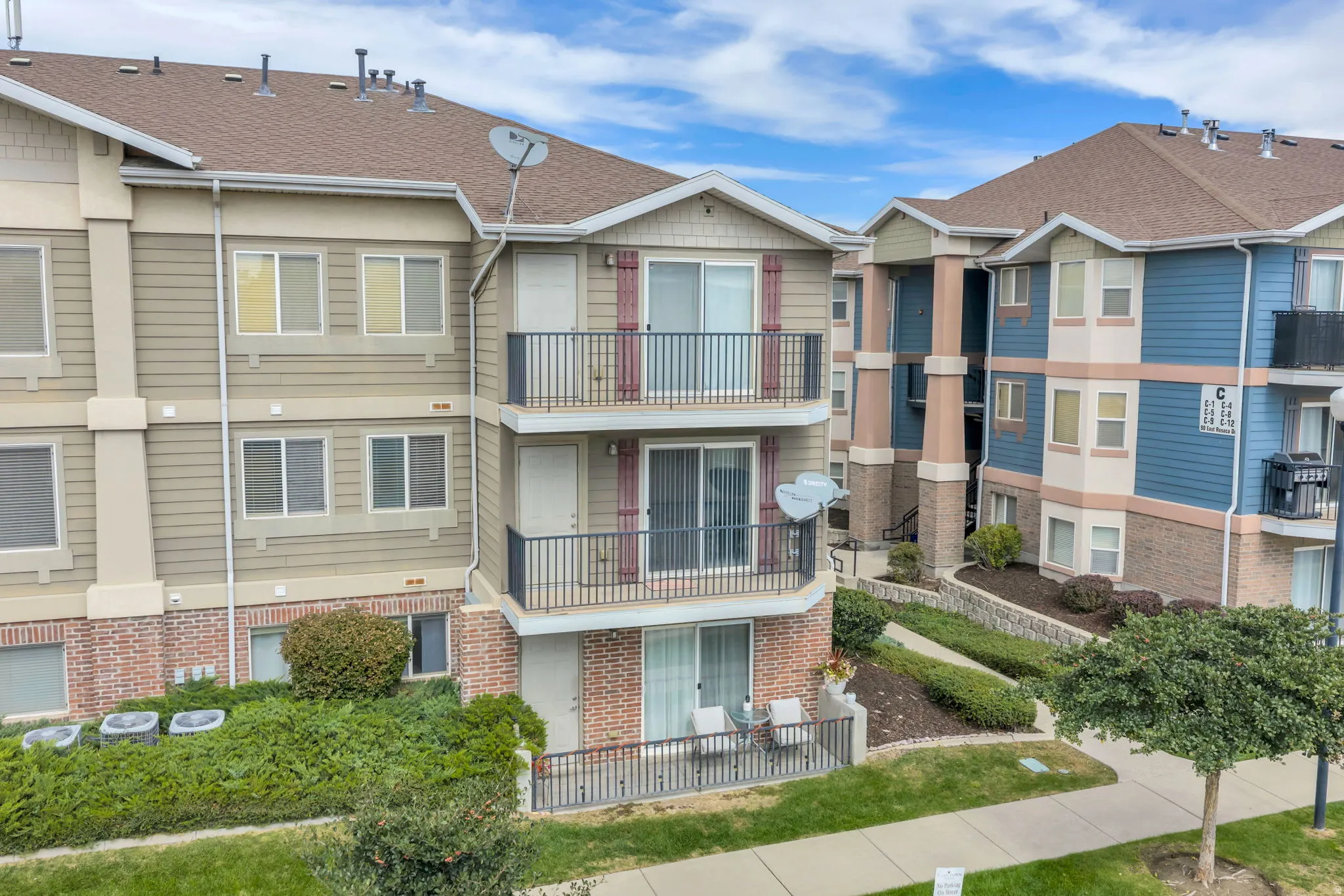 Multi-story building featuring balconies with metal railings, sliding glass doors, and brick accents