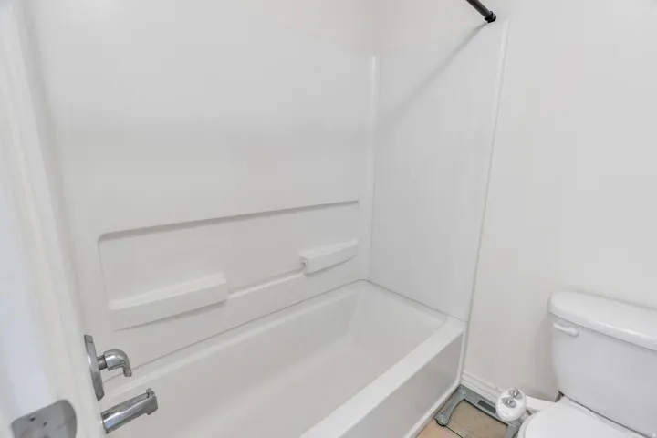 Bathtub with integrated shelving, chrome fixtures, and a white surround