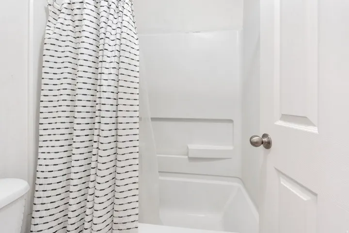 White tub and shower combination with integrated shelving