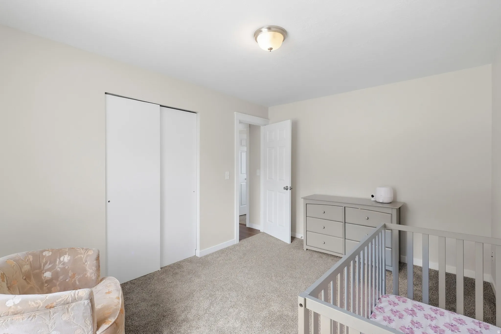 Neutral wall tones with a ceiling-mounted light fixture, soft carpet flooring, and a sliding closet door