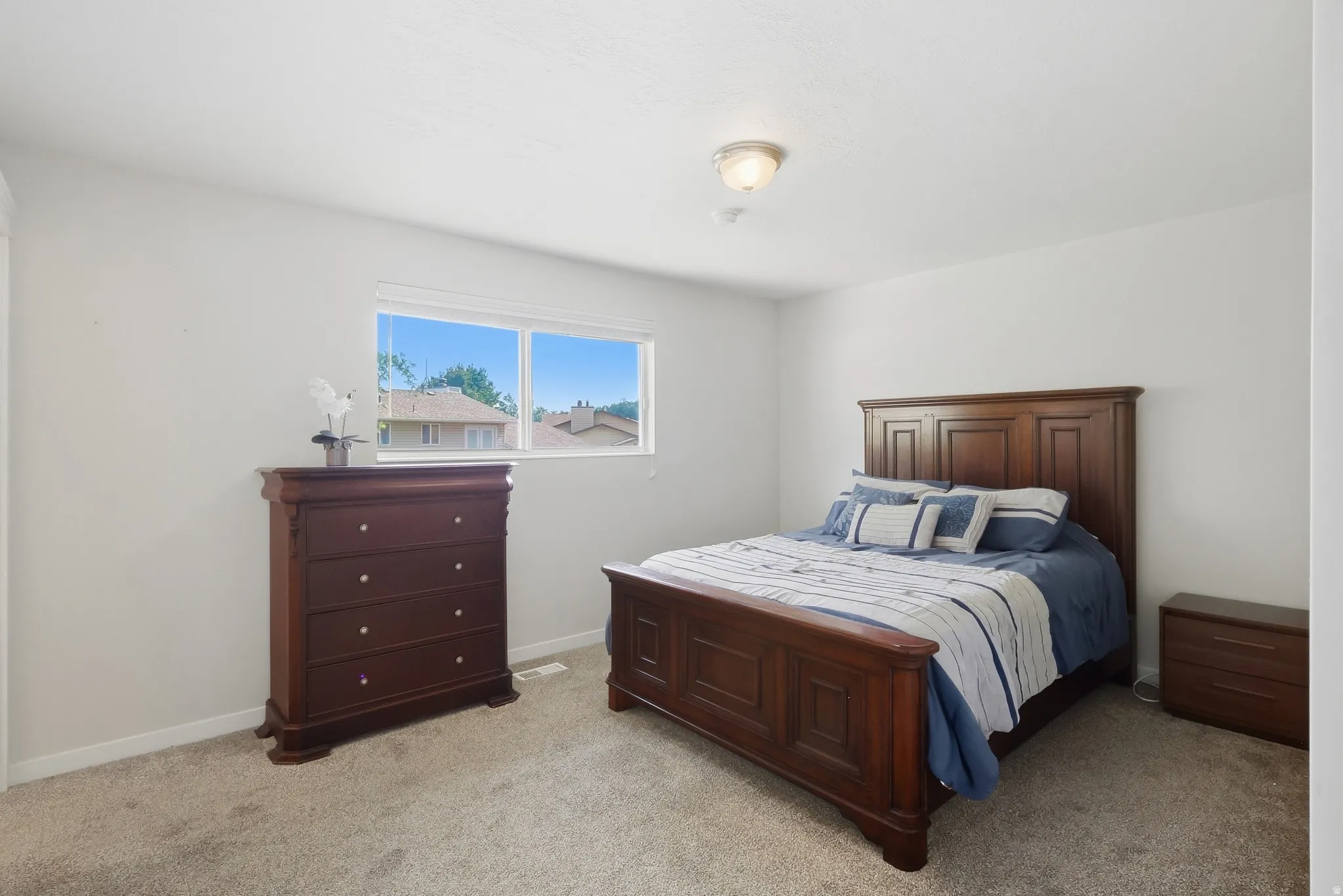 Carpeted flooring, white painted walls, and a single window with white trim