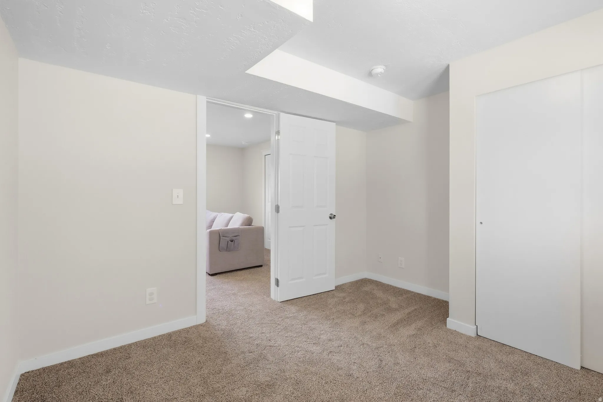 Carpeted room with white walls, white trim, and a white sliding closet door