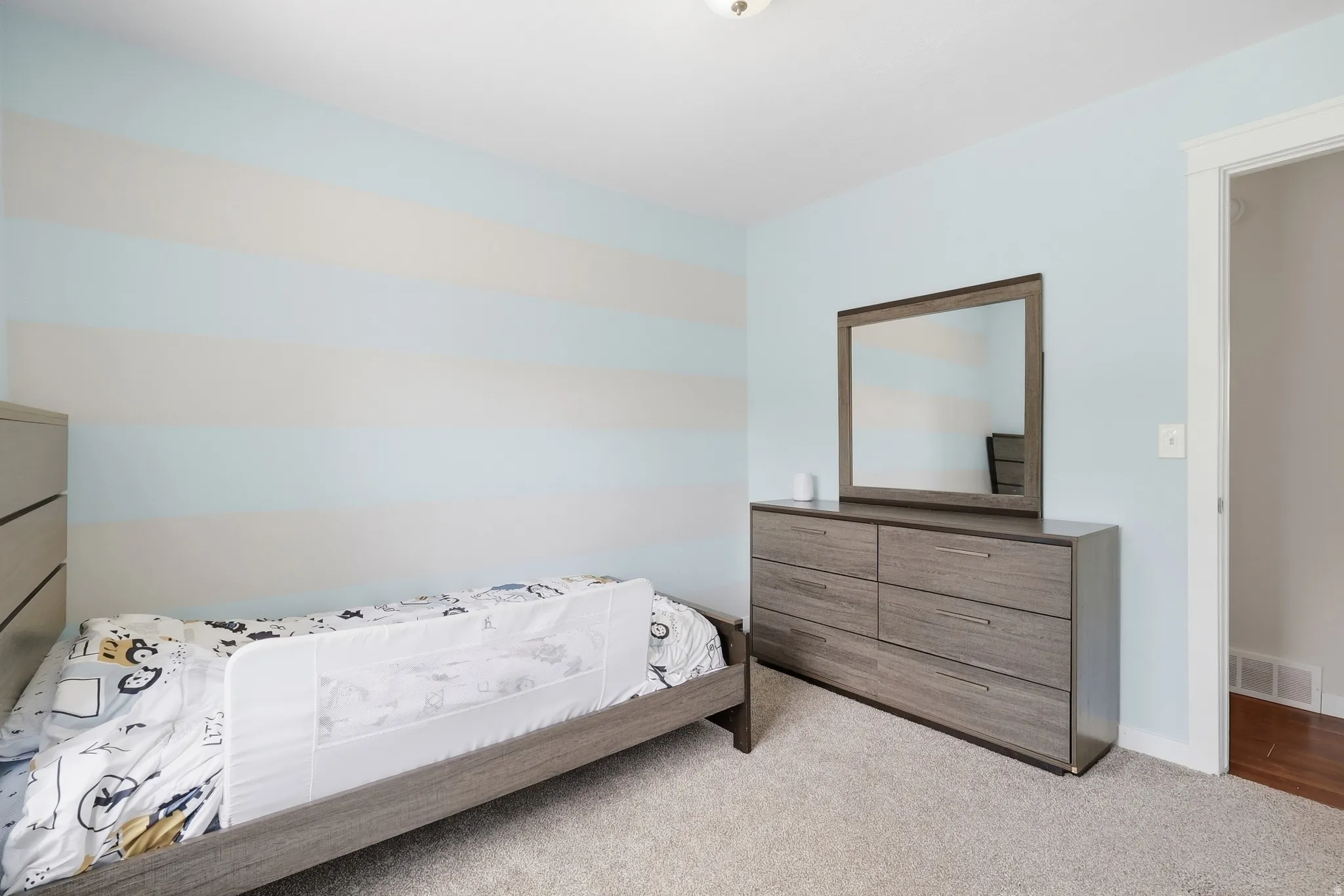 Carpeted flooring throughout, light-toned walls with horizontal banding, and an entryway with wood-finish flooring