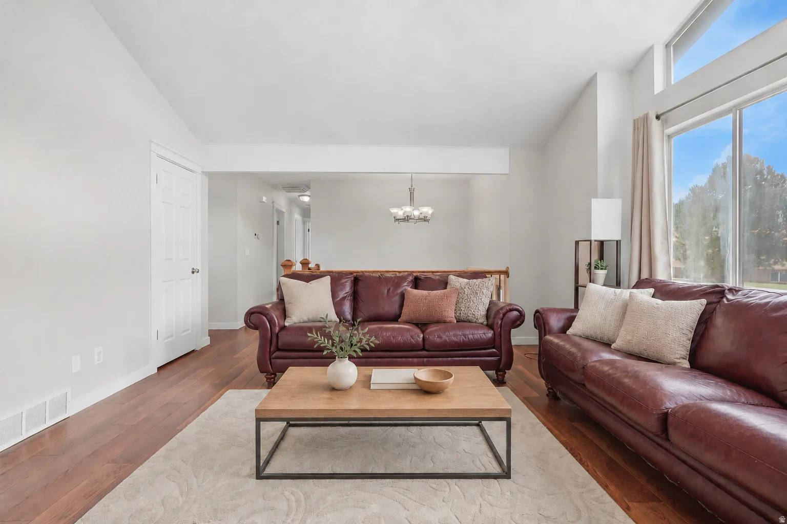 Spacious room featuring wood-finish flooring, ample natural light from large windows, and a neutral color palette