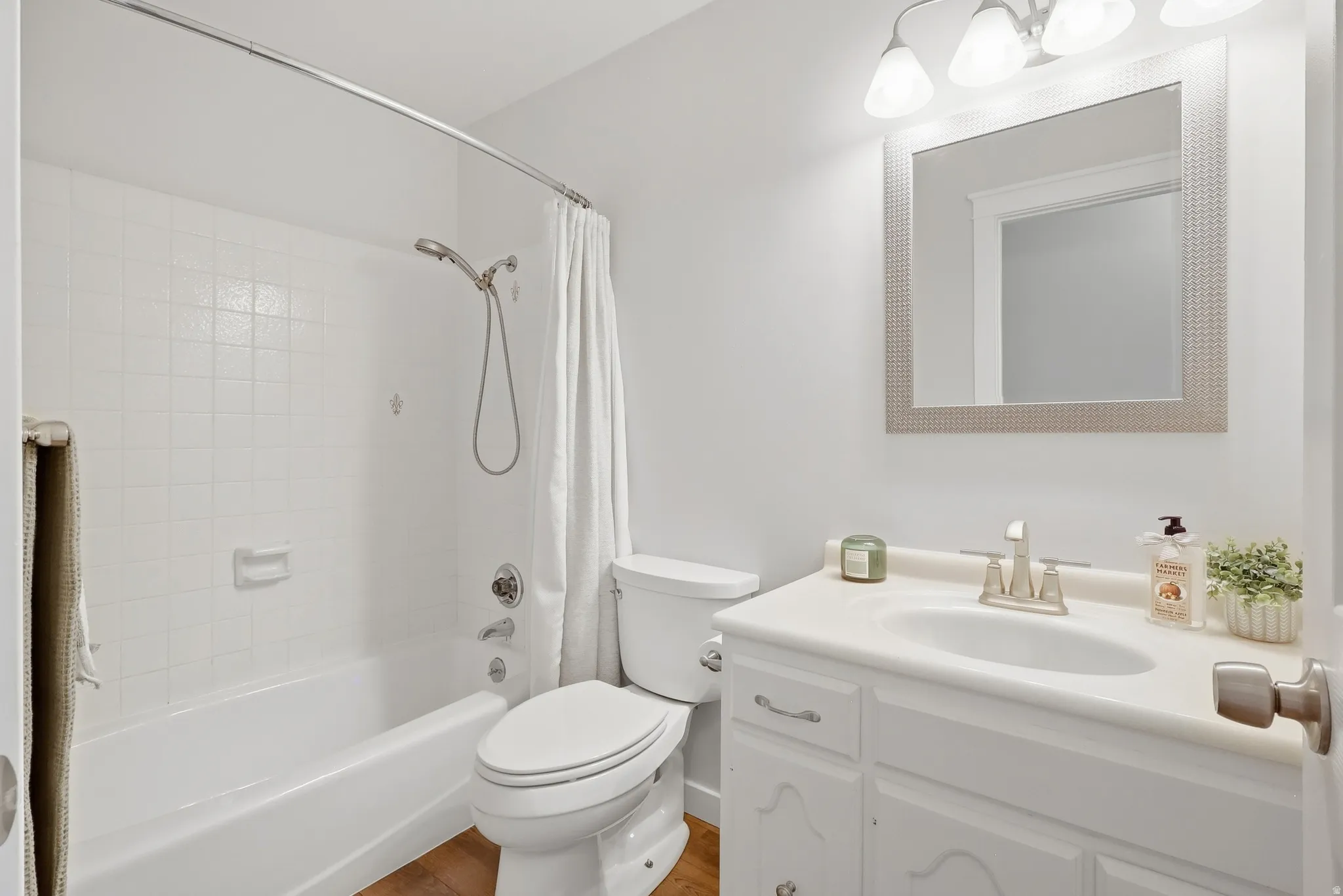 White paneled vanity with an integrated sink, brushed nickel faucet, and overhead three-bulb light fixture