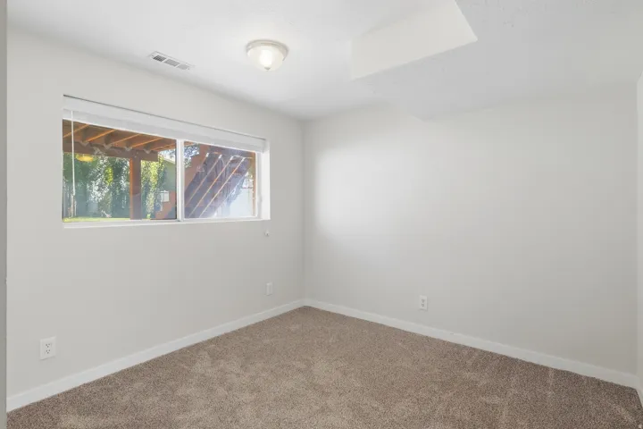 Wall-to-wall carpeting with light-toned walls, featuring a window with integrated blinds