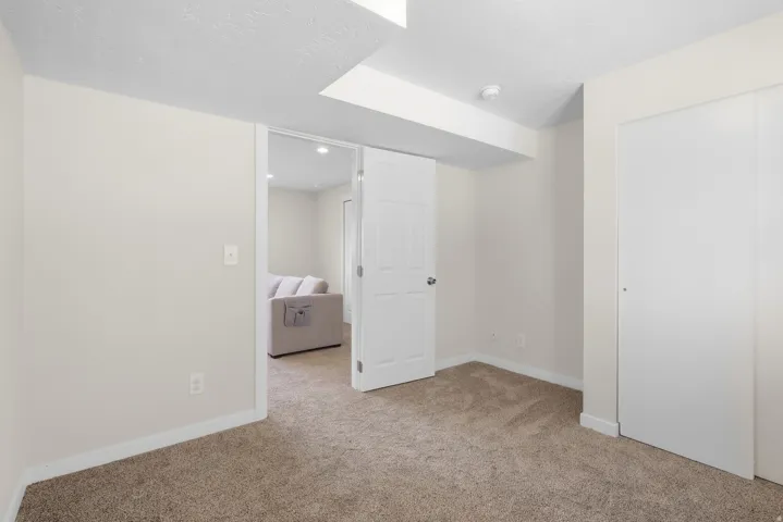 Carpeted room with white walls, white trim, and a white sliding closet door